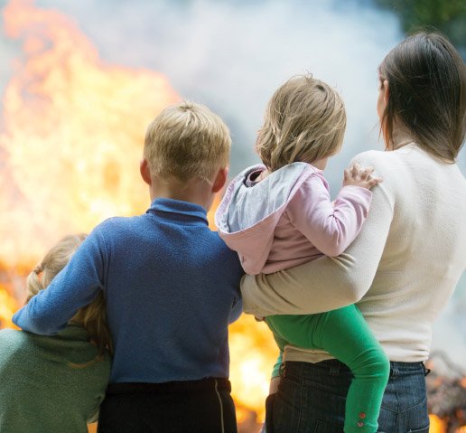 Two parents and a child watch a house burn